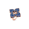 The VENETIAN PRINCESS DIAMOND AND TITANIUM FLOWER RING by Roberto Coin showcases a large four-petal flower with navy enamel and diamond accents on each petal, set in rose gold against a white background.