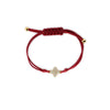 Red silk bracelet with yellow gold bead ends and a decorative pave diamond flower charm in yellow gold on a white background