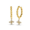 Yellow gold twisted hoop earrings with dangling diamond flowers on a white background