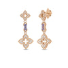 The VENETIAN PRINCESS CARNIVAL PAVE DIAMOND AND TANZANITE FLOWER DANGLE EARRINGS by Roberto Coin feature 18K rose gold, two diamond floral motifs, a rectangular tanzanite connector, and intricate stud-backed design.