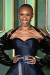 Cynthia Erivo wearing a navy and black dress with sheer sleeves against a green background