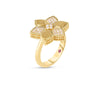 The VERNAZZA ALTERNATING PAVE DIAMOND AND SATIN FINISH FLOWER RING by Roberto Coin features a six-petal flower in 18K yellow gold with textured and pavé diamond petals, plus a pink gemstone side accent. Shown on a white background.