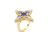 The STARDUST MEDIUM DIAMOND AND BLUE CERAMIC STAR RING by Roberto Coin is an 18K yellow gold ring with a large diamond star, blue ceramic center, diamond tips, and a small red gemstone on the band.
